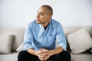Man sitting on a couch thinking to represent depression
