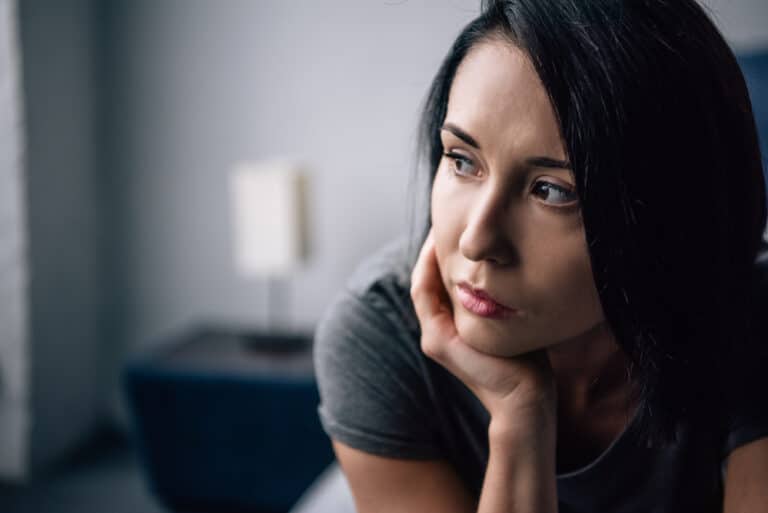 Close-up of young woman at home looking away from camera, serious expression