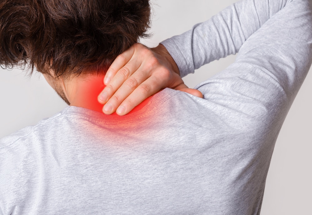 Close-up of man rubbing back of neck, painful area colored red