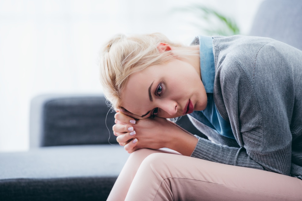 Sitting woman leaning over her thighs, looking anxious or stressed
